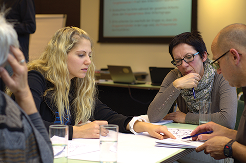 Business people sat around meeting table looking at paperwork